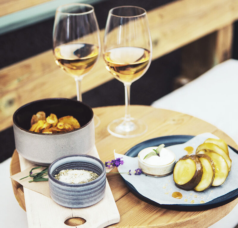Dukad bricka med snacks och två glas dryck utomhus.